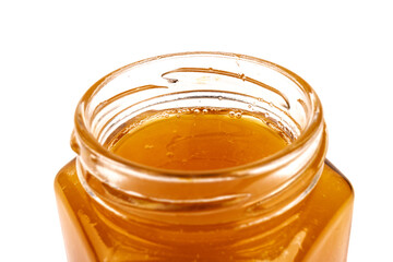 Glass jar full of sweet honey isolated on white background