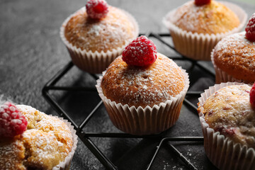 Grid with tasty raspberry muffins on dark background, closeup
