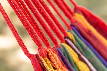 Colorful hammock with red ropes hanging outdoors on a sunny day