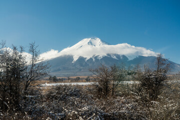 Snow covered Fuji Mountain partially obscured by clouds, during winter in Japan. 