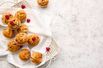 Tray with tasty raspberry muffins on light background