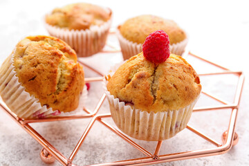 Grid with tasty raspberry muffins on light background, closeup
