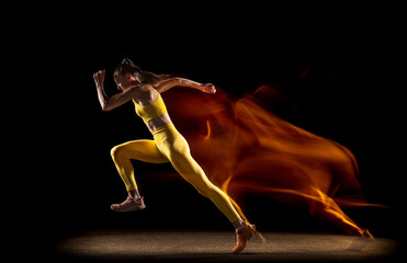 Young woman, female athlete training isolated over black studio background in mixed neon lights....