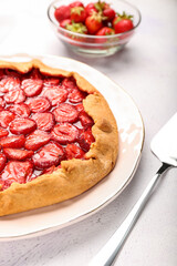 Plate with tasty strawberry pie on light background, closeup