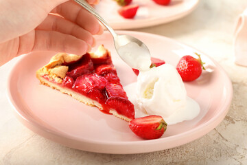 Woman eating tasty strawberry pie on light background, closeup