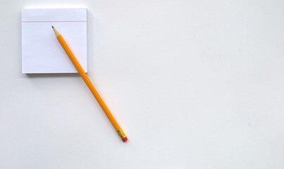 A block for writing and a pencil in the left corner on a white background