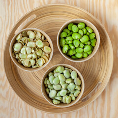 Raw fava beans in bowls. Peeled, unpeeled and separated seed skins of fava beans top view.