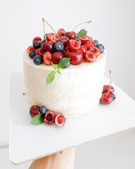 Juicy cake with white cream and strawberry cherry blueberries mint close-up