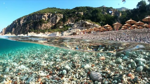 Slow-motion half underwater video at the border of air and water. Beautiful rocky beach on the Adriatic Sea in Montenegro.