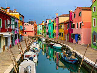 Fototapeta na wymiar Boats docking and colorful houses in a canal street houses on Burano island, Venice, One unrecognizable people on the background.