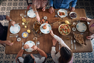 Crop friends serving delicious seafood paella at table