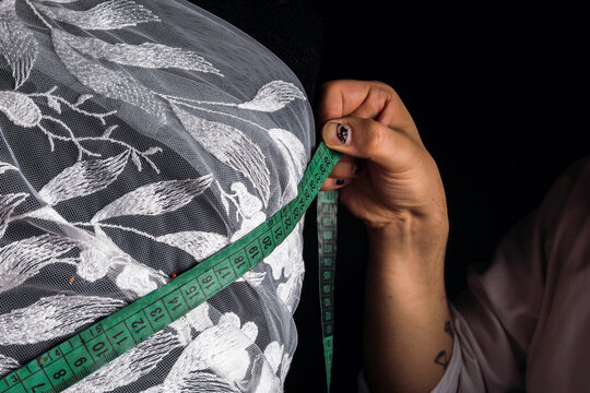 A centimeter is a tailor's tool for measuring when sewing - Close-up of satre's hands taking measurements.