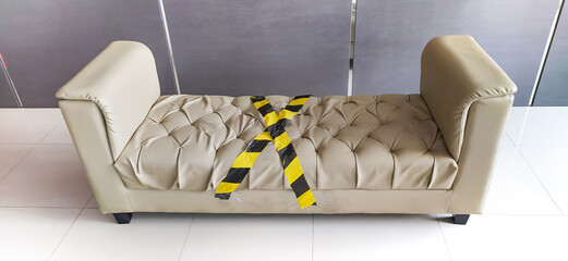 Action against COVID-19. Social distancing on one of the sofas inside the hotel lobby. The yellow...