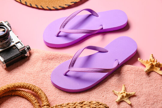 Stylish flip-flops, towel and photo camera on color background, closeup