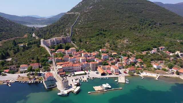 Aerial drone footage of the Mali Ston medieval old town, famous for its very long fortified wall, in Croatia on a sunny summer day
