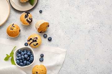 Composition with tasty blueberry muffins and berries on light background