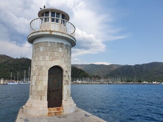 A small lighthouse in a bay by the sea.  The lighthouse serves as a signpost for sailors.