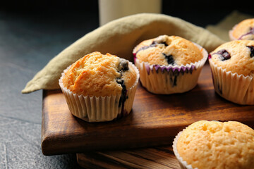 Tasty blueberry muffins on dark background, closeup