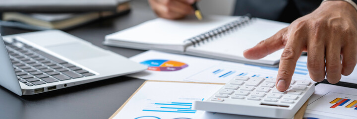 A male accountant or a business man uses a laptop to calculate investment results. And making...