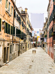 Fototapeta premium Colorful dead end street in Venice with lots of laundry hanging out to dry in lines stretched between the houses