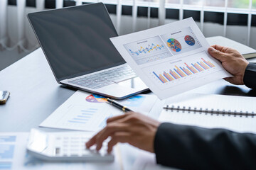 Businessman discussing analysis charts or graphs on desk table and using a laptop computer. Close up male analysis and strategy concept.
