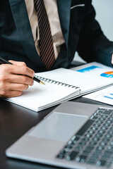 A male accountant or a business man uses a laptop to calculate investment results. And making financial reports on the desk Business finance accounting concept