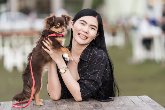 Portrait of a beautiful girl playing with her lovely puppy at outdoor in the public park. Little dog with owner spend a day at the park playing and having fun. Pet love stock photo
