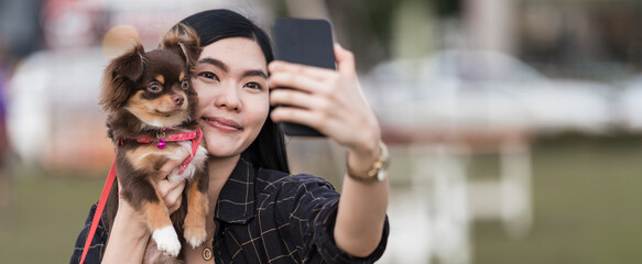 Portrait of a beautiful girl playing with her lovely puppy at outdoor in the public park. Little...