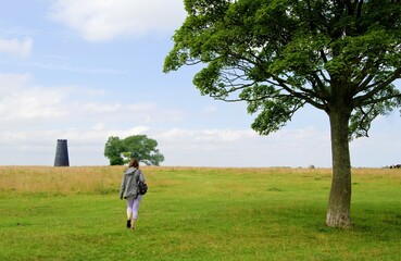 Fototapeta premium Woman approaching a black disused windmill, in Beverely, in the East Riding of Yorkshire, England.