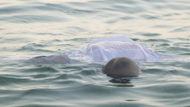 The body of a drowned man floats on the water near the shore