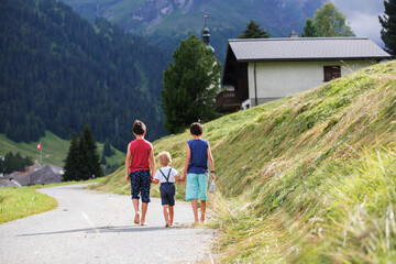 Happy family in Switzerland, walking on a mountain little road, going on vacation