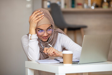 Smiling Muslim girl student wear wireless headphone study online with skype teacher, happy young...