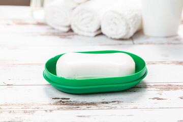 new soap on a green plastic soap dish, on a white wooden background.