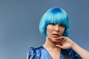 Short haired trendy girl with cool makeup in fashionable blue bright clothes looking into camera on isolated background..