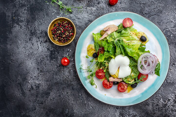 Tuna salad with poached, egg, lettuce, cherry, tomatoes olives and corn on dark stone or concrete background. Top view. copy space