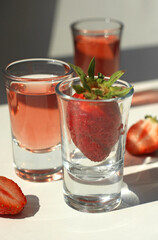 Fototapeta na wymiar strawberry compote tincture with ice in glass glasses with strawberries and ice cubes