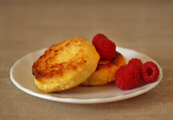 Homemade cheesecakes with cottage cheese with fresh raspberries on a beige background