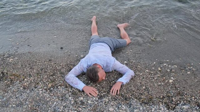 A man who swam out after a storm lies unconscious on the seashore