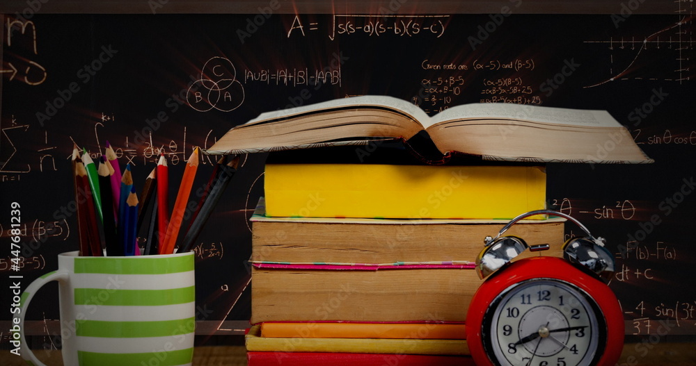 Poster a table with a pile of books, a cup with pens, and an alarm clock with mathematical equations in the