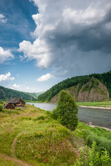 Fototapeta premium Landscape of Siberia. Kiya River, mountain banks and green forests in the Kemerovo region. Daytime landscape with blue skies and clouds.