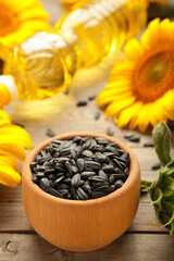 Sunflower seeds and bottle of oil on grey wooden table.