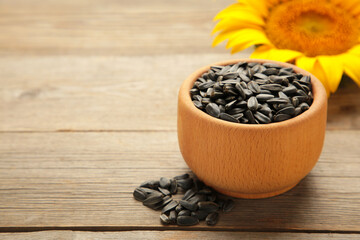 Sunflower with seeds in bowl on grey wooden background