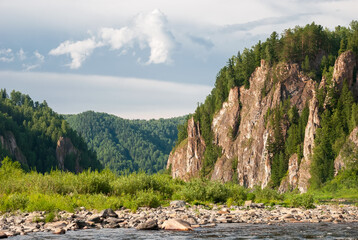 Fototapeta na wymiar Landscape of Siberia. Kiya River, mountain banks and green forests in the Kemerovo region. Daytime landscape with blue skies and clouds.