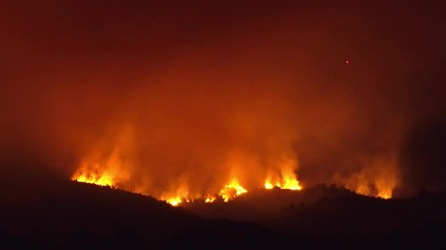 Masive Mountain Forest fire over mountain landscape glowing at night