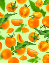 Tomatoes pattern. Flying ripe fresh yellow orange tomatoes with green leaves on green background flat lay. Cherry tomatoes. Vegetables, healthy vegan organic food, harvest concept. Creative layout