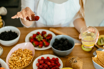 Close up of female hands holding homemade berry pastille with nuts and berries ingredients on table at kitchen. Pastille and fruit, healthy snacks concept.