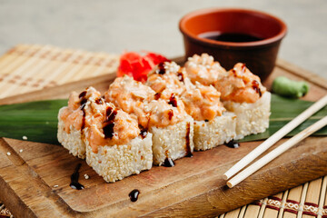 rolls with fish and filling served with soy sauce on a board