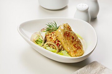 Turkey fillet with garnish and sauce. Baked turkey with bulgur, quinoa and vegetables. Restaurant dish. Cooked poultry with garnish. Food styling and food photography. Copy space. Light background