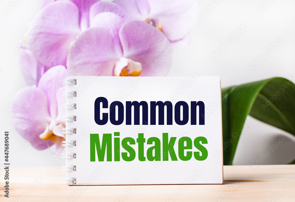 Aufkleber white blank notebook with the text common mistakes on the table against the background of a light pi