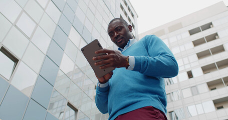 Low angle view of afro-american businessman using digital tablet outdoors